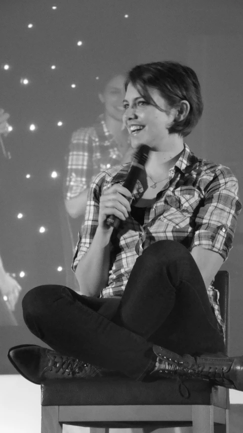 a smiling woman on a chair with a microphone