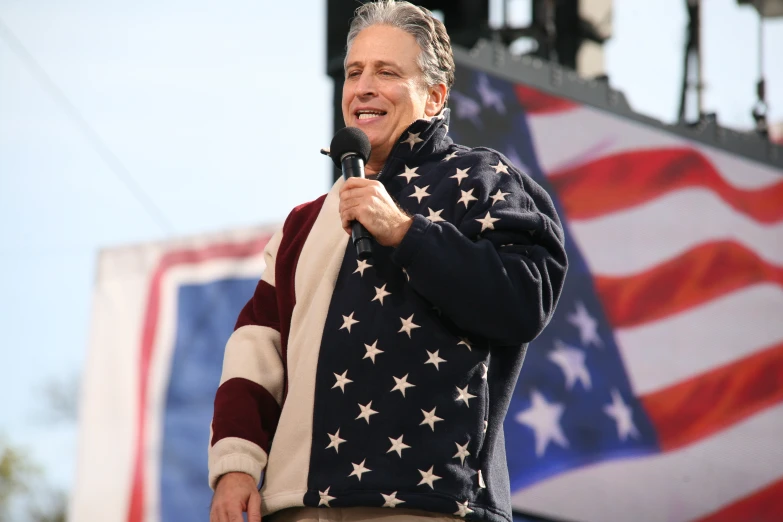 the man is singing a song in front of the american flag