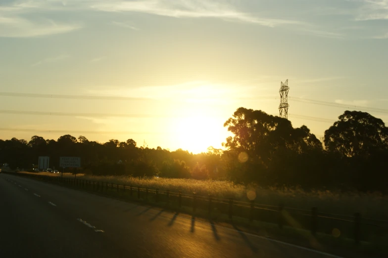 a view of the sun rising over trees in a rural area