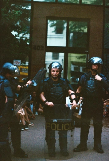 policemen in helmets stand behind an out - of - focus camera outside a building