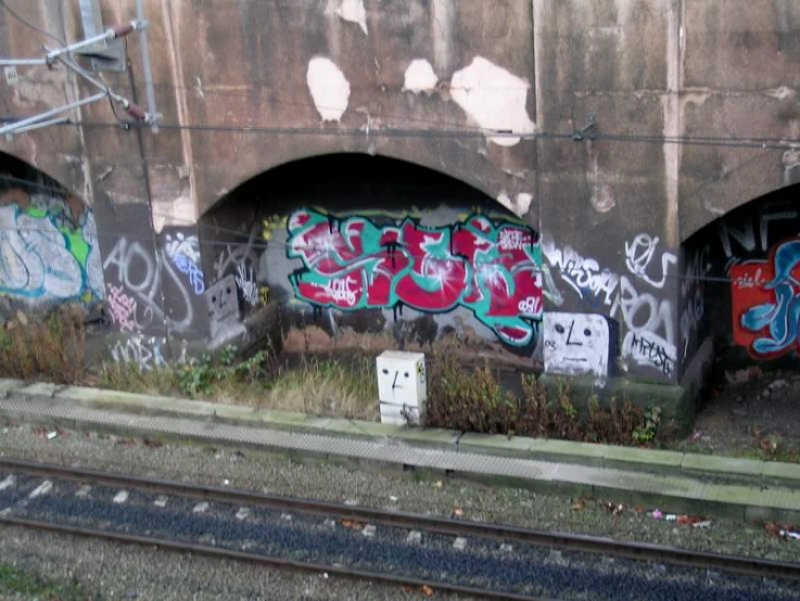 a train track with graffiti on it that is below a bridge