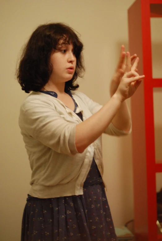 woman standing in front of a red shelf and holding a glass