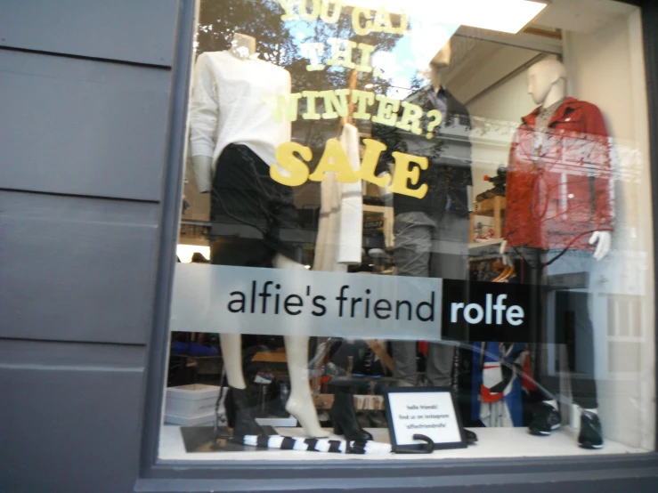 a window with a couple of mannequins and signs inside