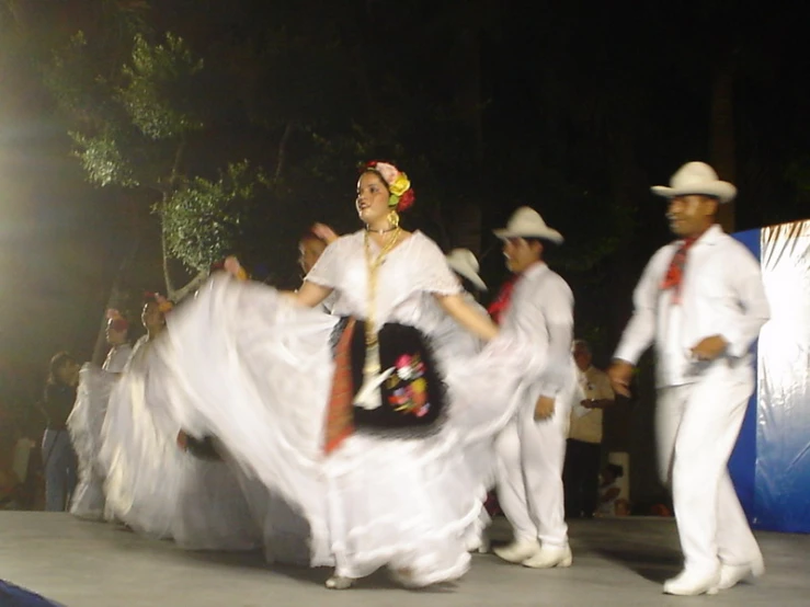 several women in white dresses dancing on a street