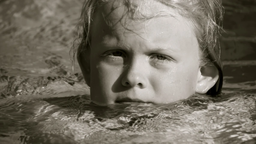 a small child is submerged in water with his head sticking out of the water