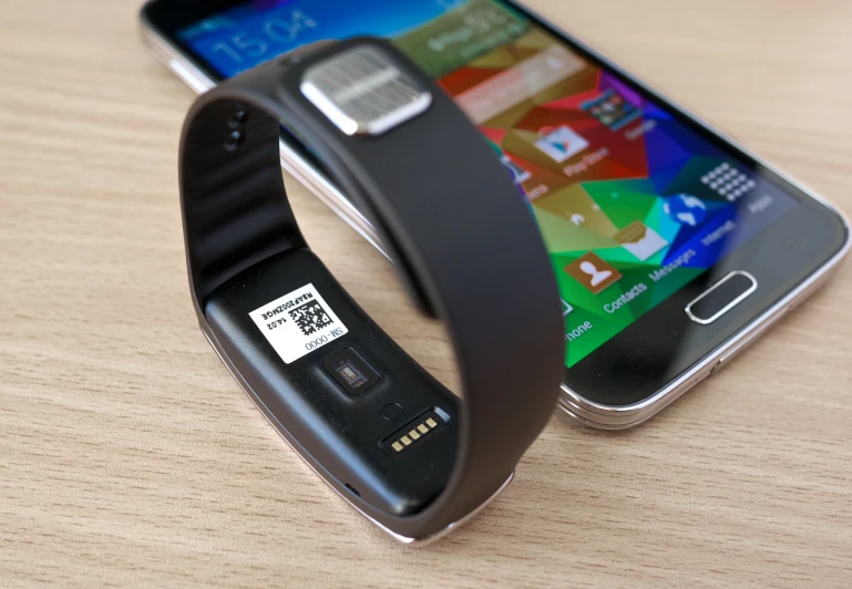 a cell phone charging on a wristband with an electronic device behind it