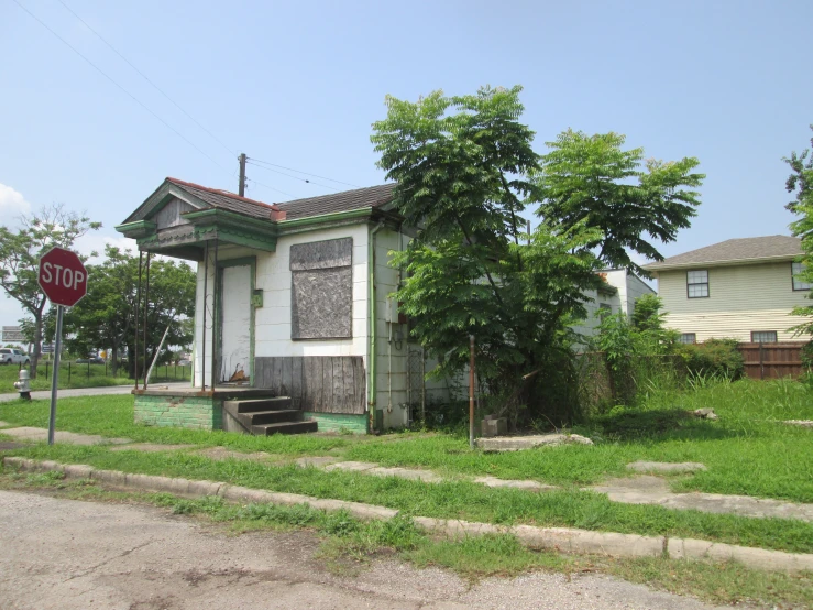 a small house has boarded up windows and a sign on the grass
