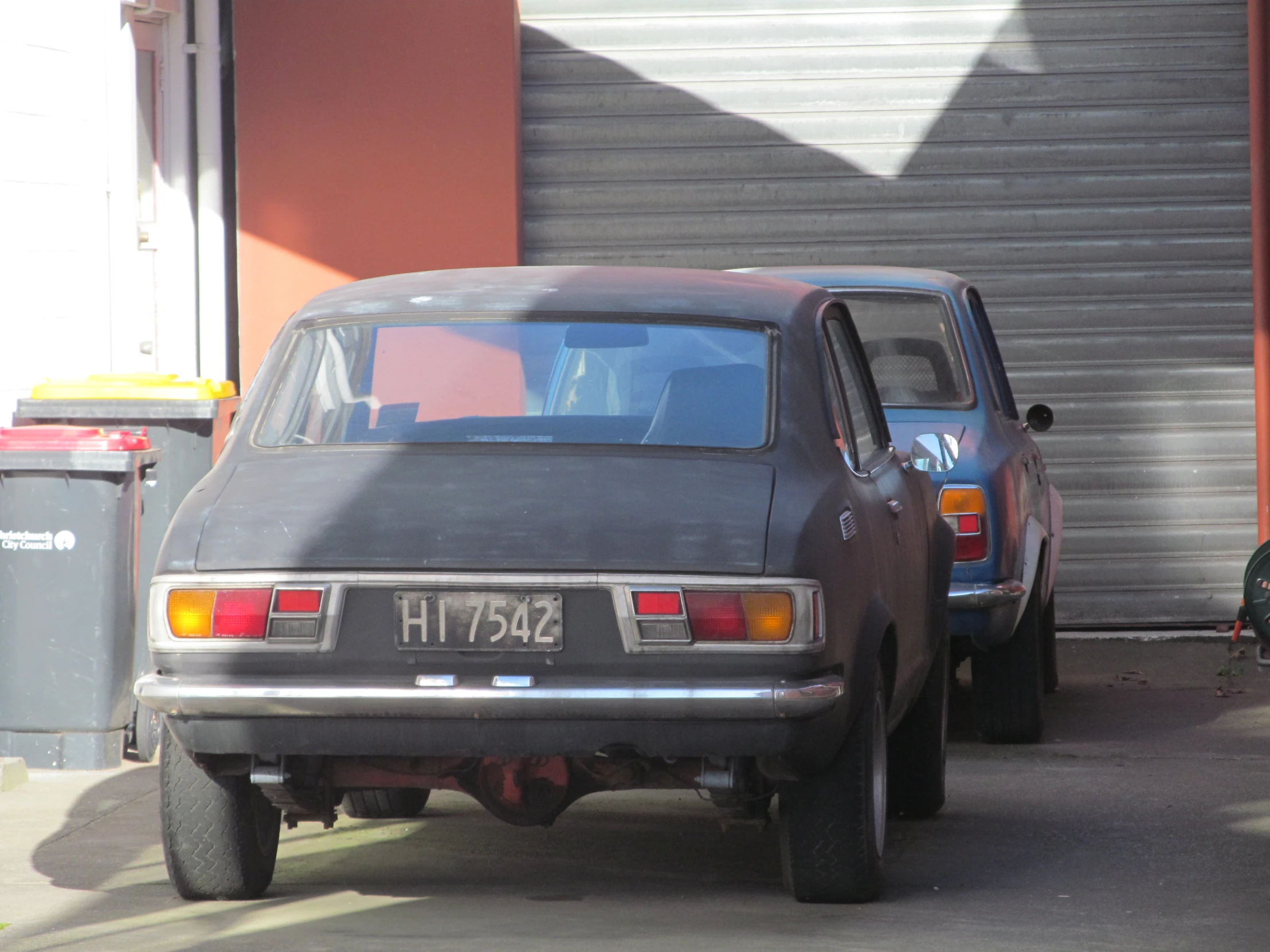 a car parked by a red building that is under a garage door