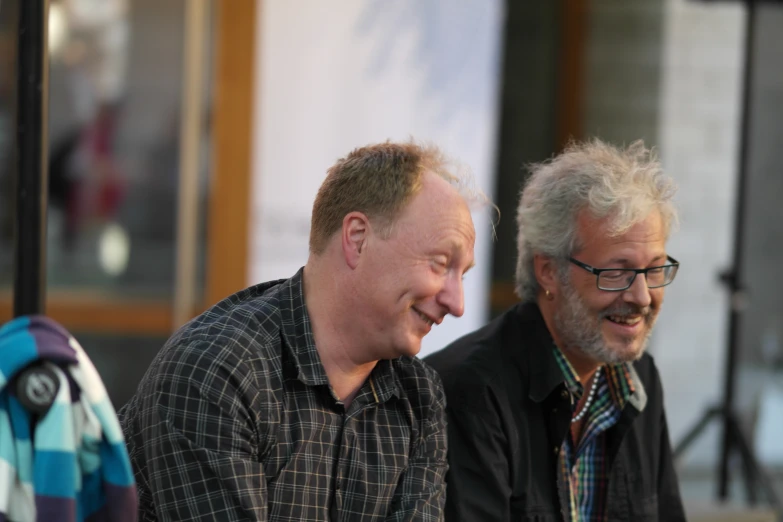 two men smile while having a conversation together