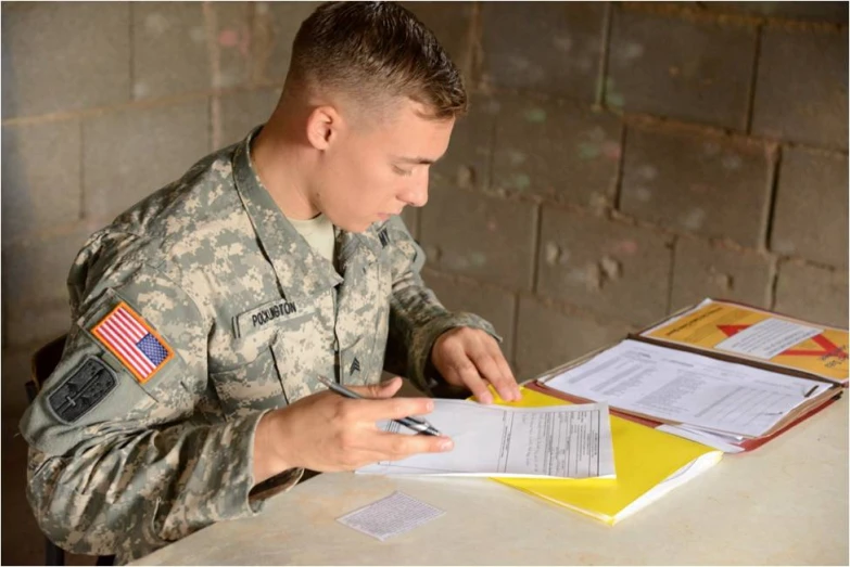 a man in the military is writing at a desk