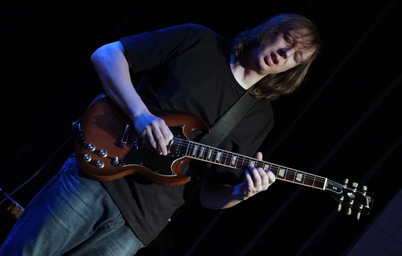 a man in black shirt playing an electric guitar