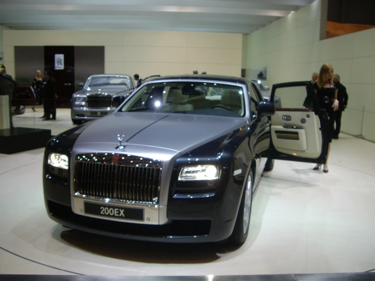 a rolls royce on display in a showroom with people walking by