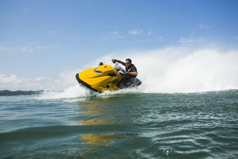 a yellow jet ski being pulled by a man in the ocean