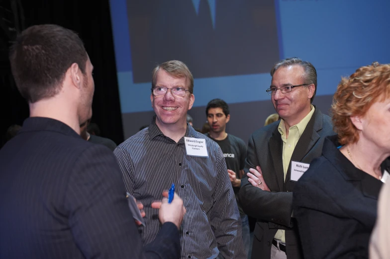 several people are smiling and discussing on the stage