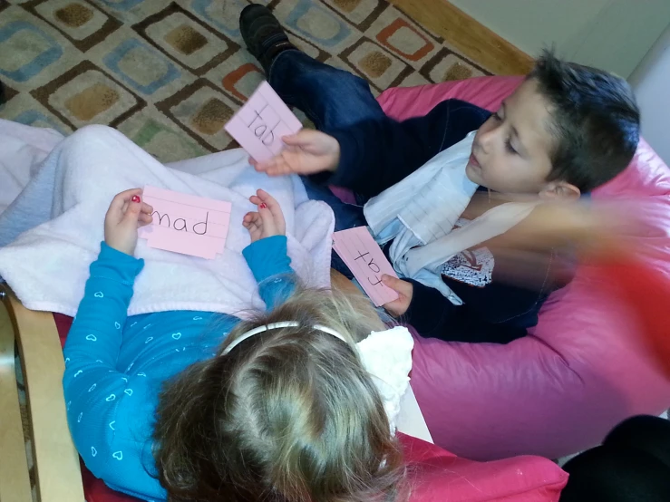 two children who are sitting on the floor with pink sticky notes