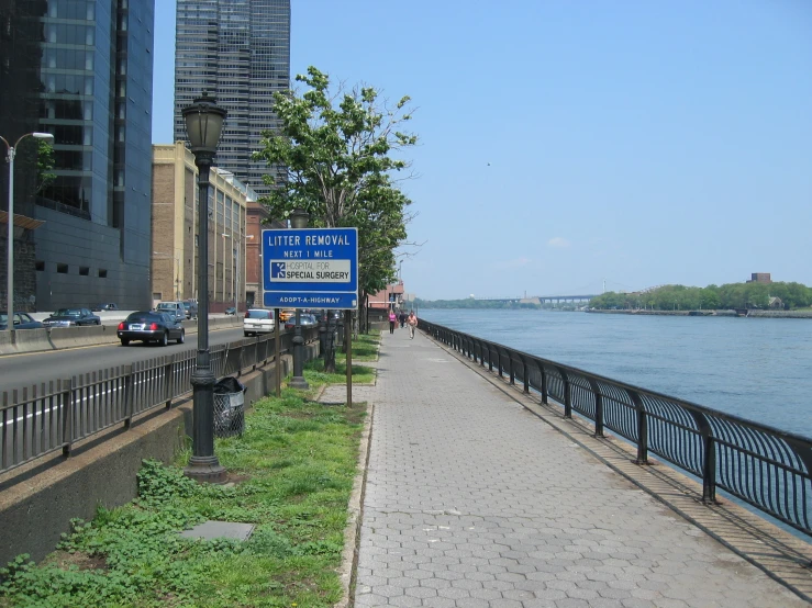 a city side walk beside the water and an industrial area