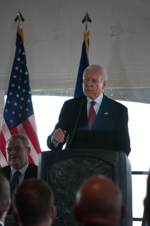 a man in a suit standing at a podium while speaking