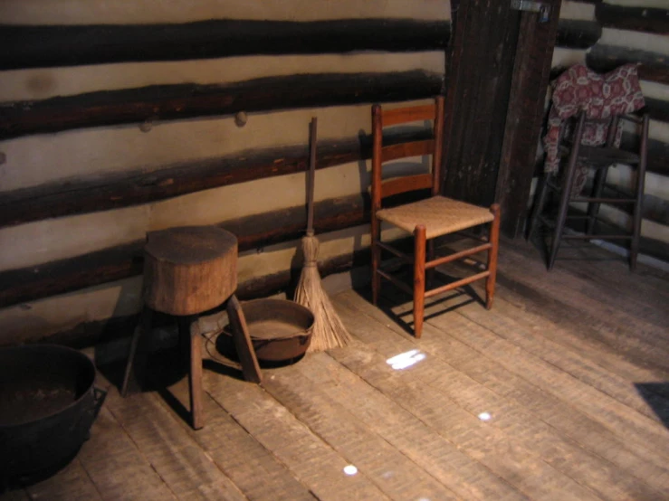 three different types of mop brush and bucket on the floor in an old log cabin