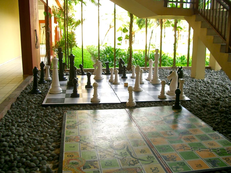 a collection of chess pieces sits on a checkered floor next to stairs