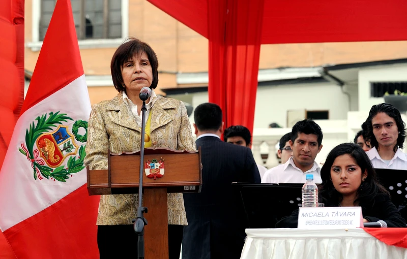 a woman stands behind a podium with a microphone in front of a group of people