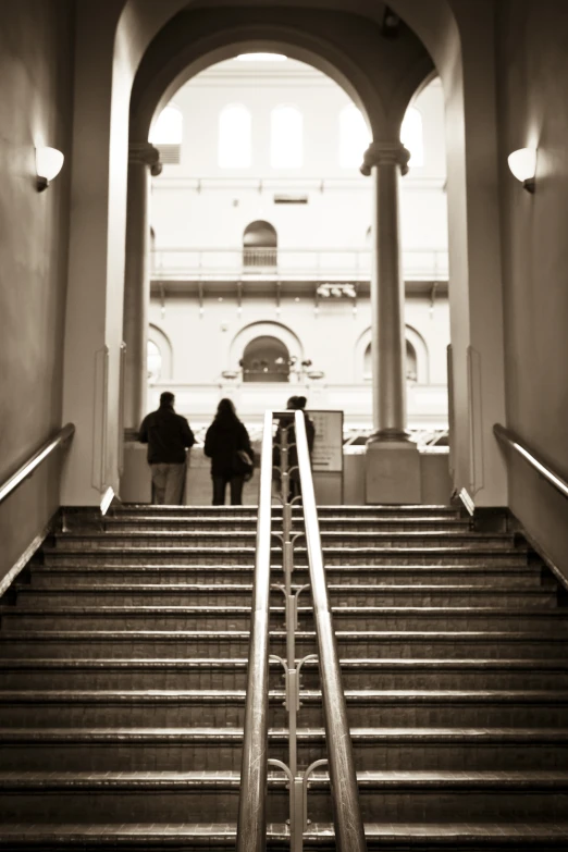 two people stand at the bottom of an escalator