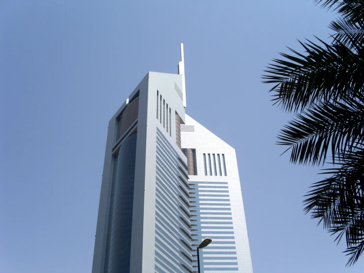 tall building against a bright blue sky in front of palm tree