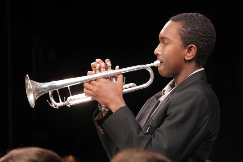 young man playing trumpet in orchestra looking into distance