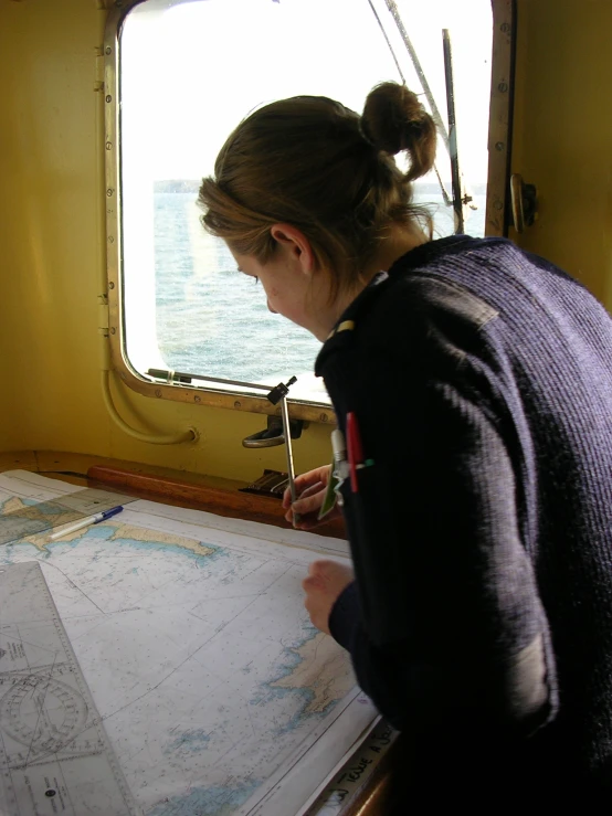 the girl looks at an ocean map in front of a window