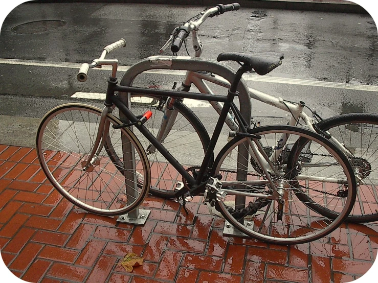 a couple of bicycles sit on the brick sidewalk