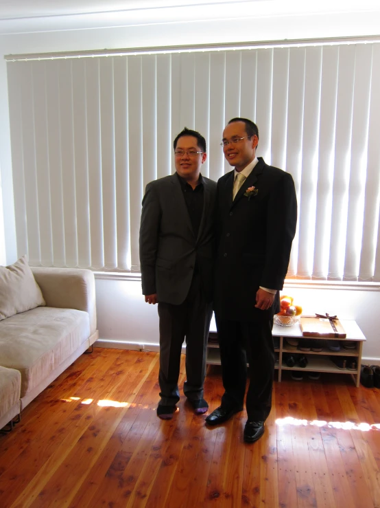 two men in suits stand together in the living room