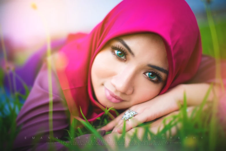 woman in a pink hijab laying on grass