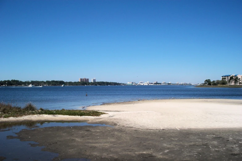 an inlet with buildings in the distance from the beach