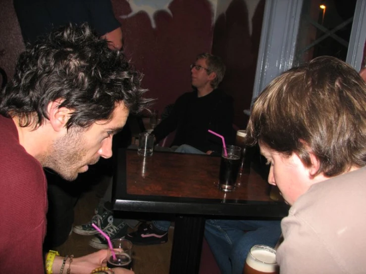 two people sitting in a restaurant, one of them using his cell phone