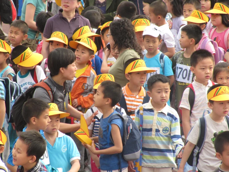 a bunch of small children in hats in front of other s