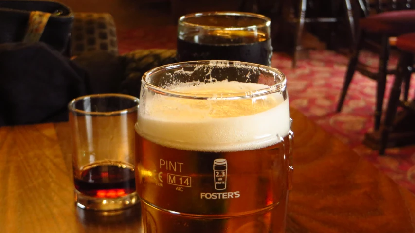 a glass filled with light beer next to two glasses
