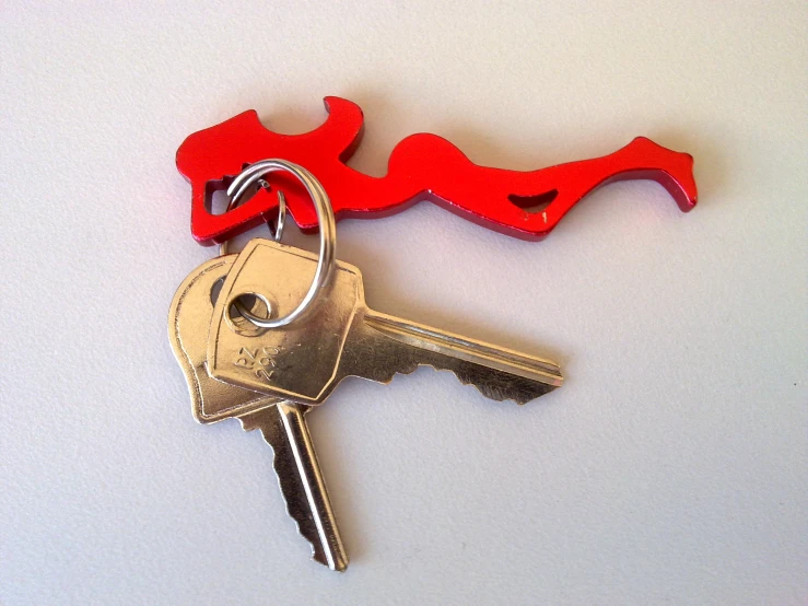 a red and gold metal key laying on top of a white surface