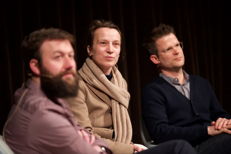 three people sitting in front of a stage