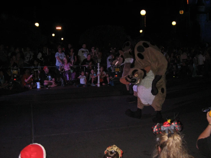 a large brown bear walking in front of a crowd