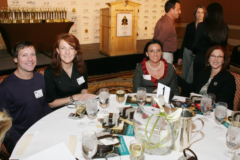 four people sitting at a table together smiling for the camera