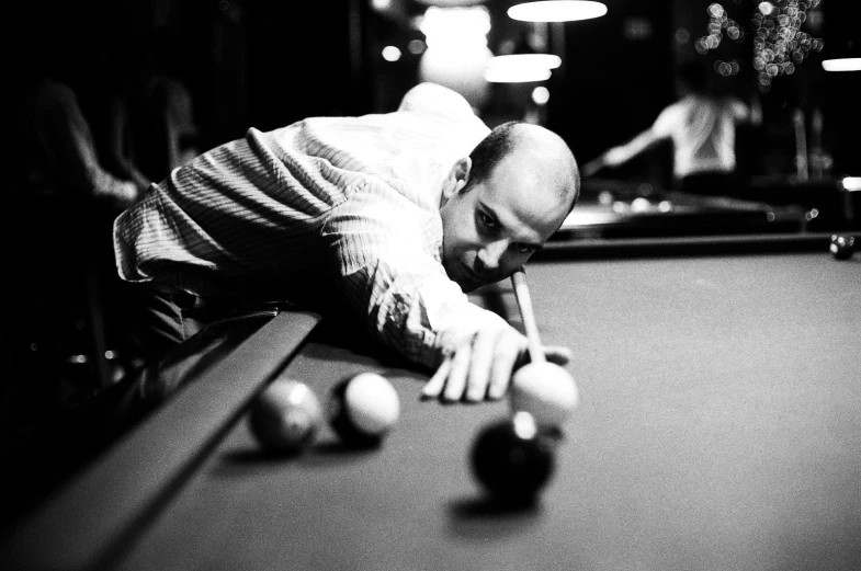 a man in a white shirt leaning over a pool table