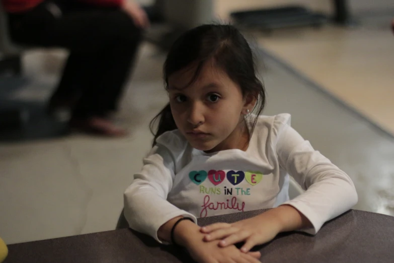 a  sitting at a table in front of an object