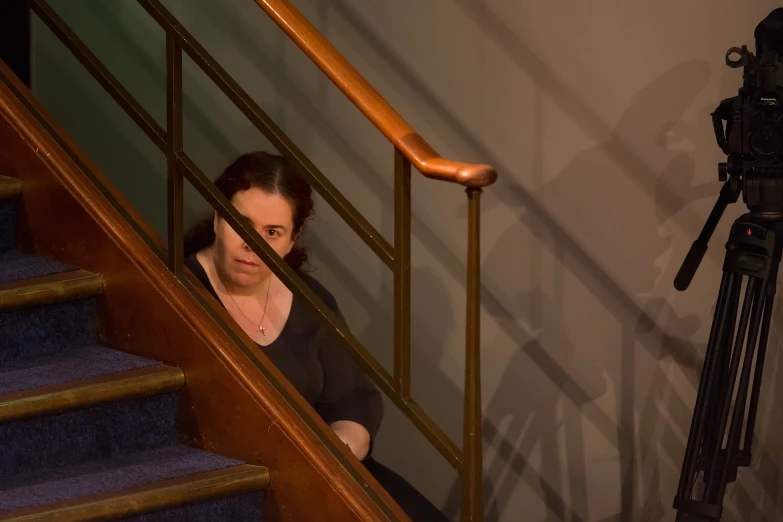 a woman is looking down from the stairs