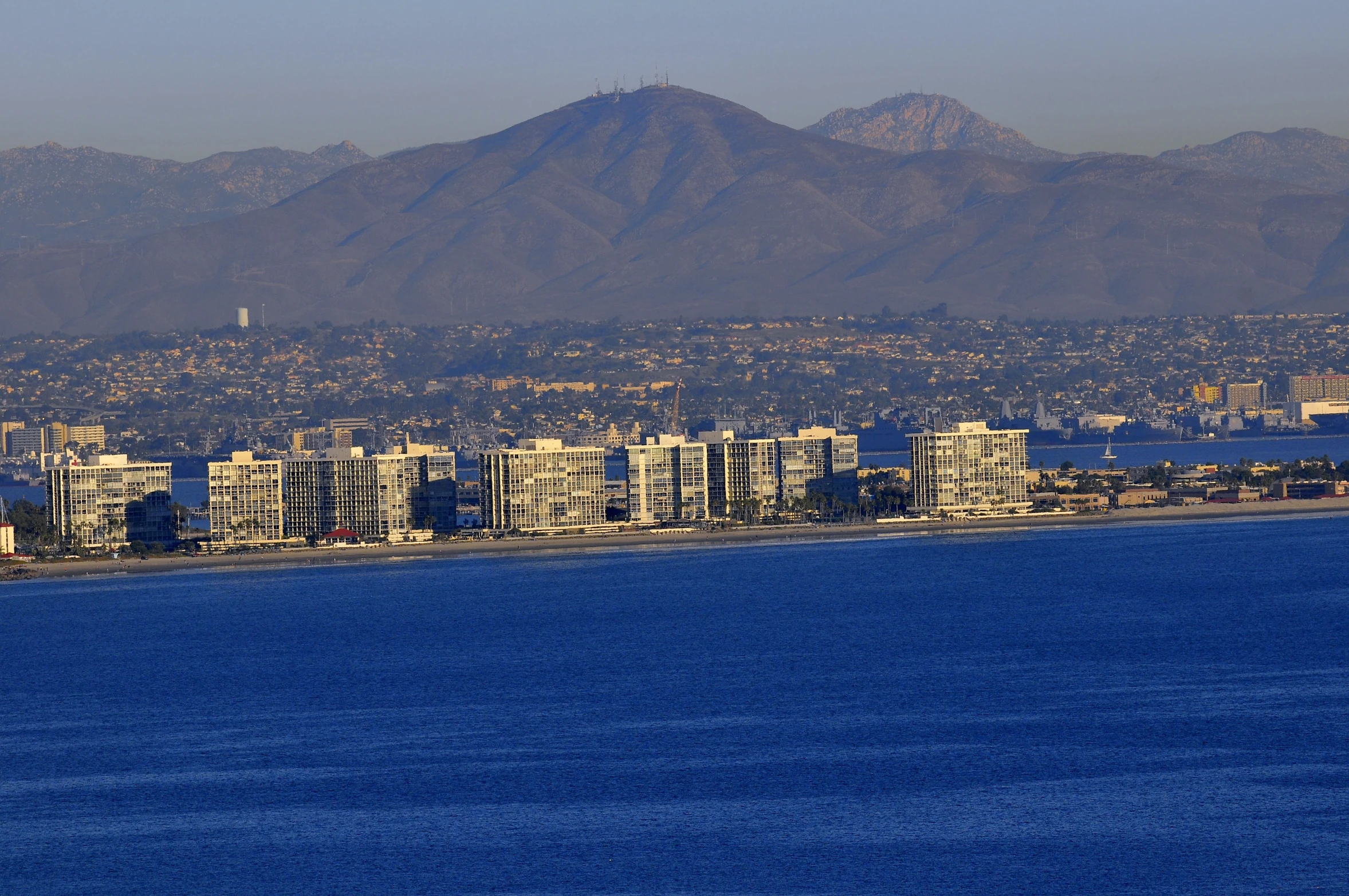 there are buildings along a waterfront with mountains in the background