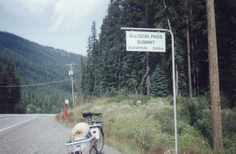 a bicycle with a basket on the back of it's tail is stopped on a mountain road