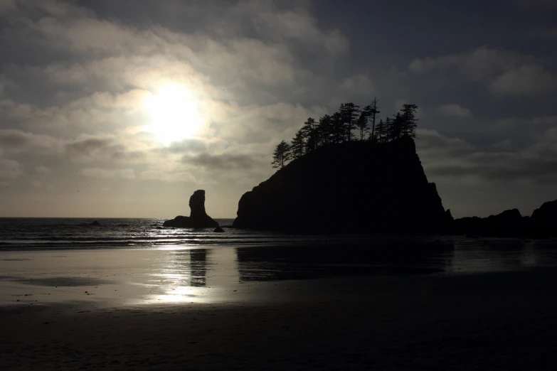 sun going down over a hill and ocean