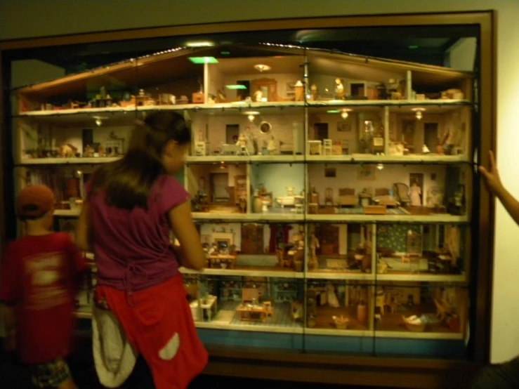 two children looking at dolls inside a display case