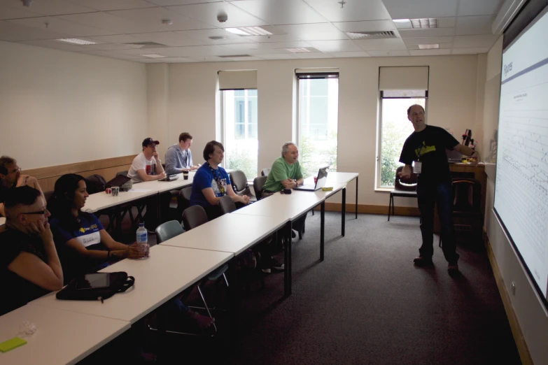 an instructor is giving a presentation in front of a room full of students