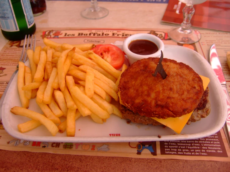 the white tray has fries, a fried hamburger and tomato salad on it