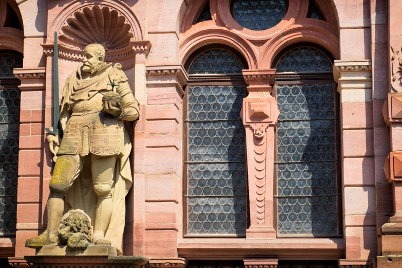 a statue stands in front of a pink building