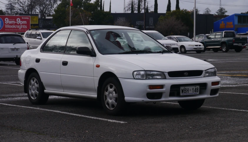 a white toyota is parked in a lot with other cars